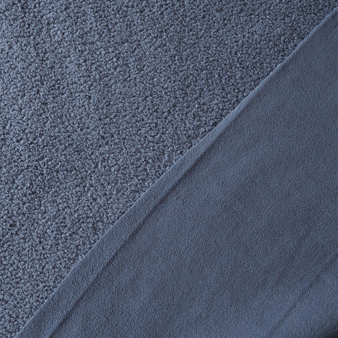 Close-up of a dark slate blue textured fabric, showing a looped pile on one side and a smoother brushed surface on the other, divided diagonally.