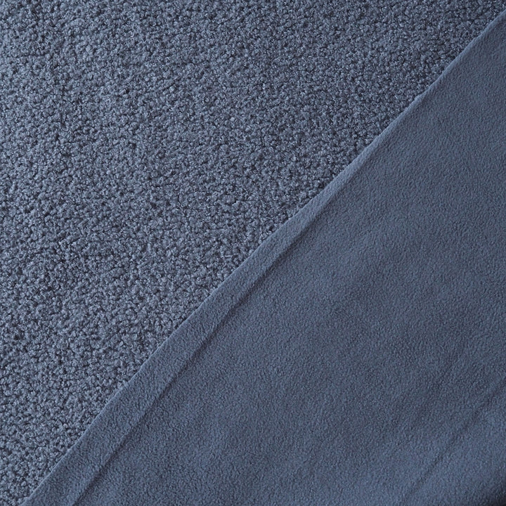 Close-up of a dark slate blue textured fabric, showing a looped pile on one side and a smoother brushed surface on the other, divided diagonally.