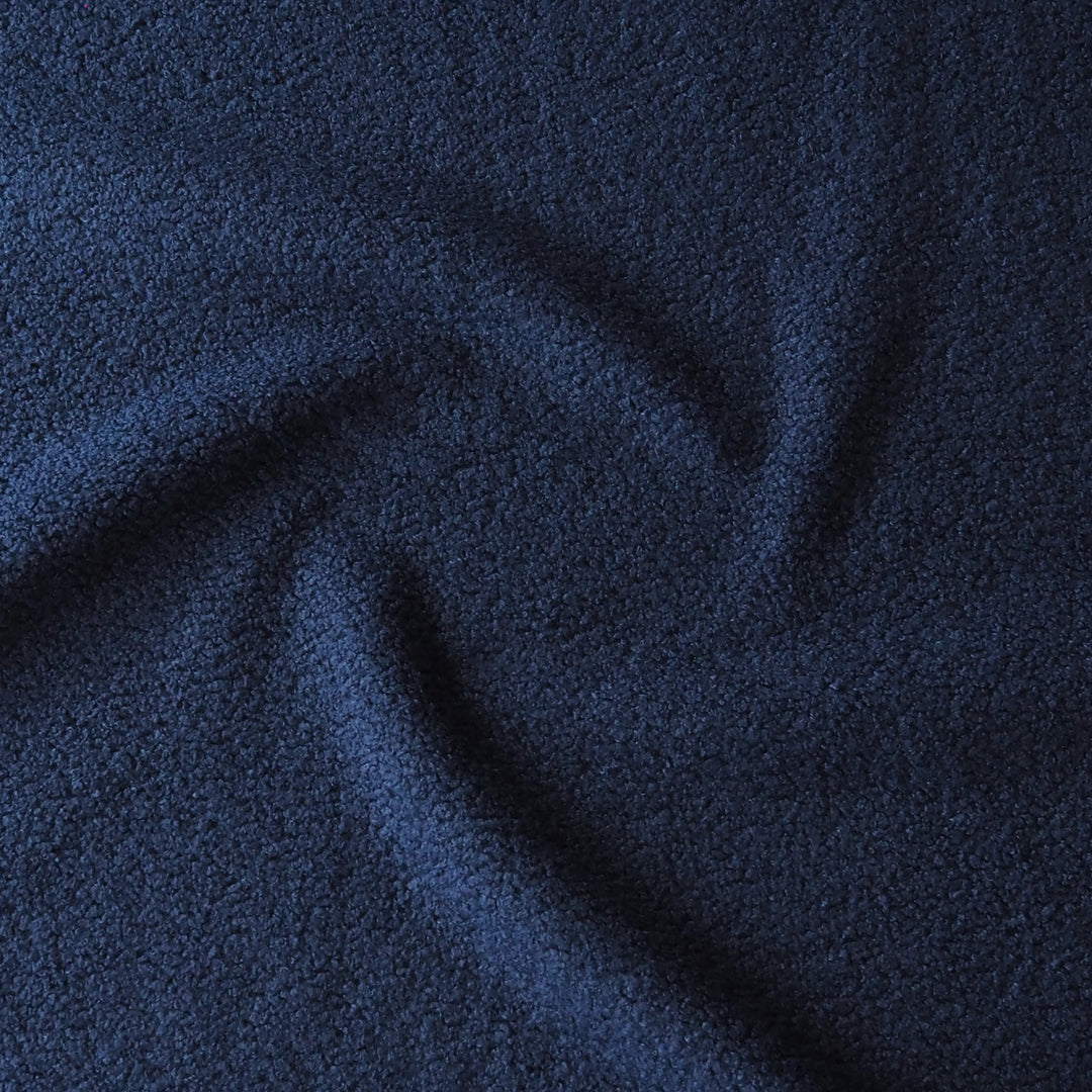 A close-up of dark navy blue textured fabric with soft folds and a slightly nubby, plush surface.