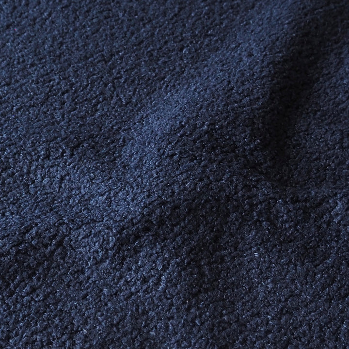 A close-up of dark navy blue textured fabric with a soft, slightly fuzzy surface.