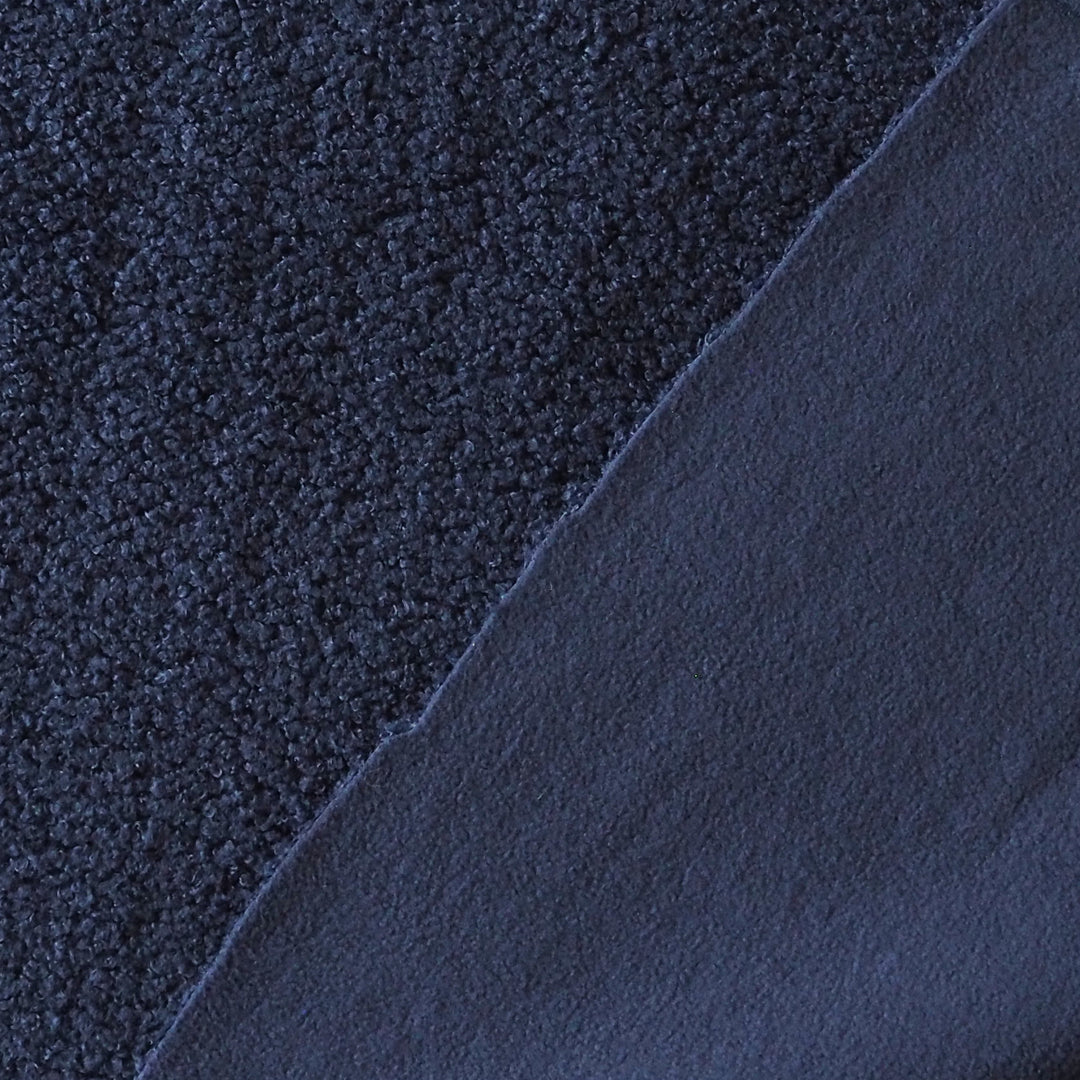 A close-up of dark navy blue fabric showing two different textures: a coarse, looped pile on the left and a smoother, matte finish on the right, divided diagonally.