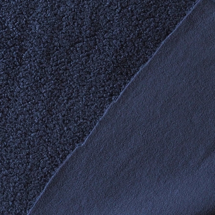 A close-up of dark navy blue fabric showing two different textures: a coarse, looped pile on the left and a smoother, matte finish on the right, divided diagonally.