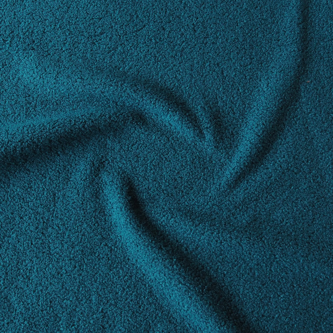 A close-up of textured fabric in a deep teal blue color, shown with soft folds and swirls.