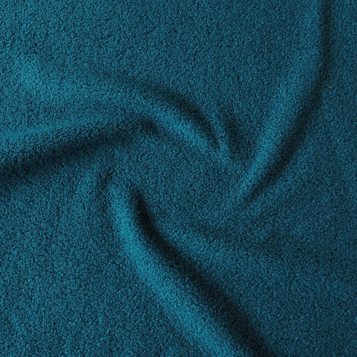 A close-up of textured fabric in a deep teal blue color, shown with soft folds and swirls.