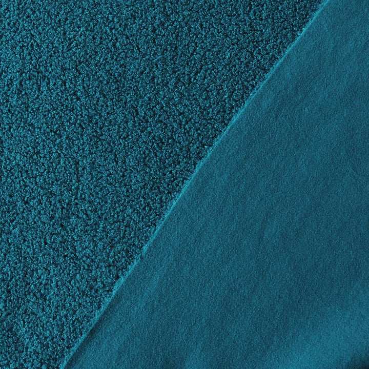 A close-up of teal fabric showing two different textures: a coarse, nubby bouclé texture on the left and a smoother, matte fabric on the right, divided by a diagonal seam.