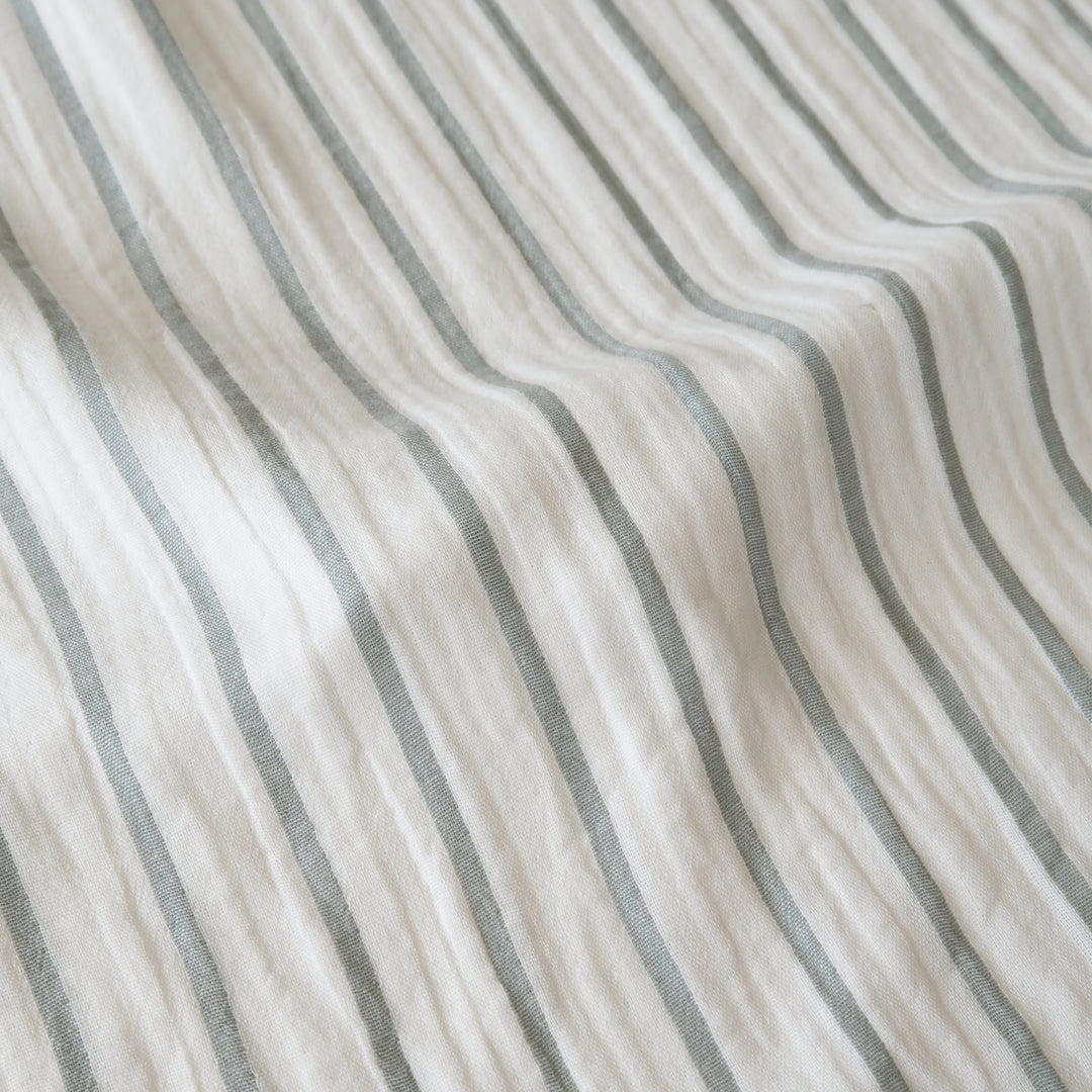 Close-up of a textured fabric with vertical stripes in muted gray on an off-white background.