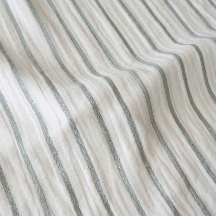 Close-up of a textured fabric with vertical stripes in muted gray on an off-white background.