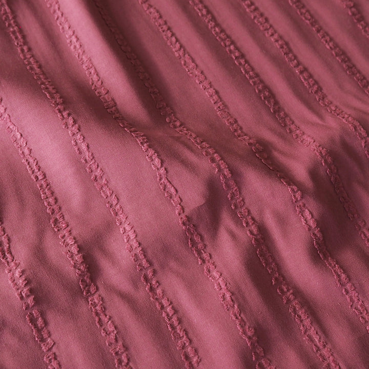 A close-up of dusty rose pink textured fabric with vertical stitched stripes.