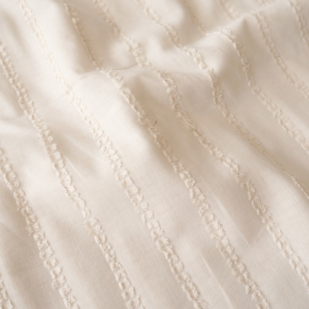 A close-up of a cream-colored fabric with a textured vertical stripe pattern.
