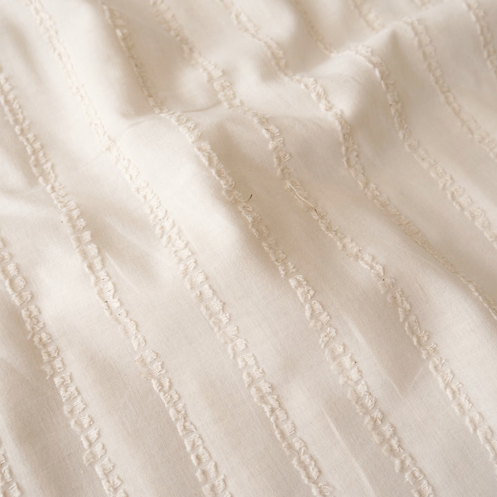 A close-up of a cream-colored fabric with a textured vertical stripe pattern.