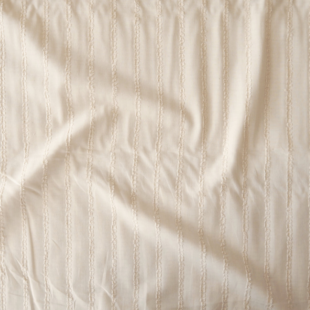 A close-up of a cream-colored fabric with a textured vertical stripe pattern.
