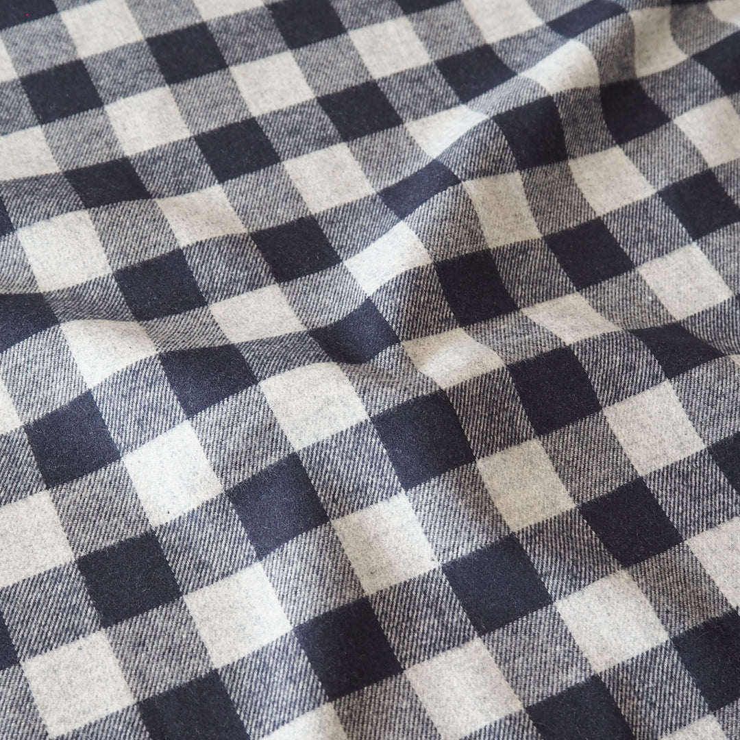 A close-up of a black and off-white gingham plaid fabric with a soft, draped texture.