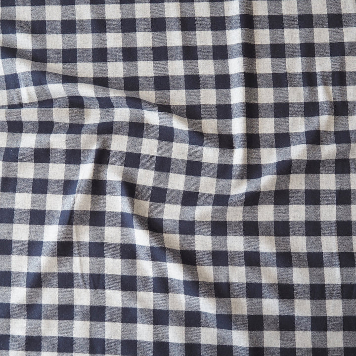 A close-up of a navy blue and off-white gingham checkered fabric with soft folds.