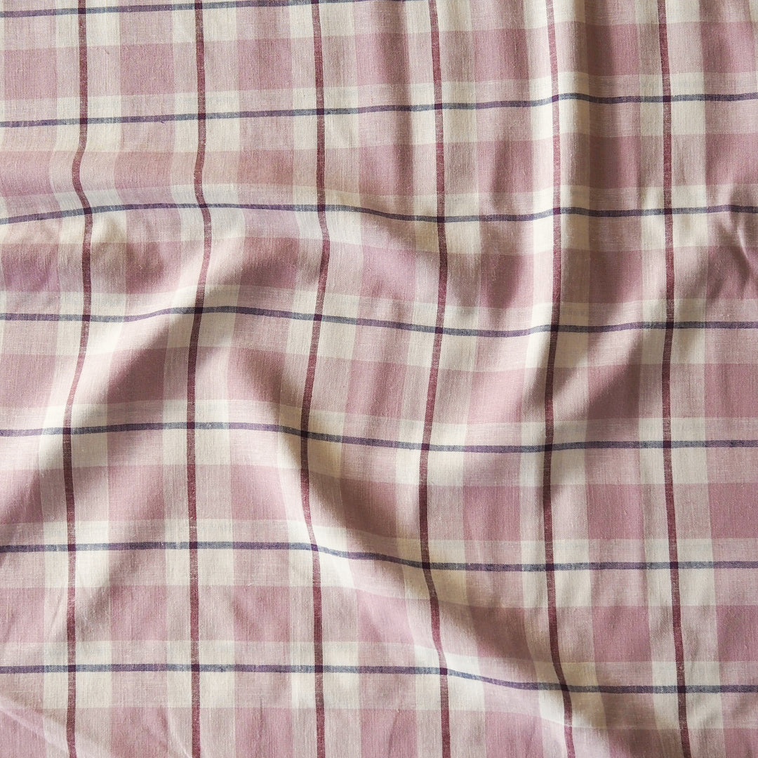Pink and off-white plaid fabric with thin dark purple stripes, shown with soft folds and wrinkles.