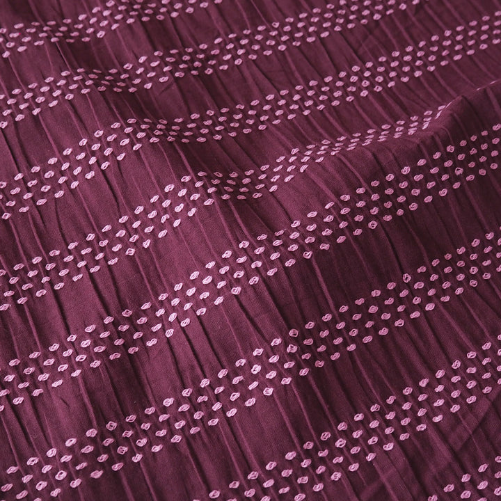 A close-up of a pleated fabric in a deep plum purple color, decorated with horizontal rows of small light pink embroidered dots.