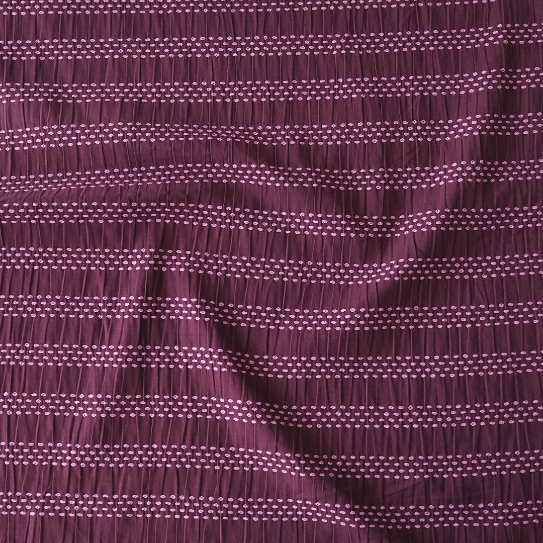 A close-up of a textured fabric with a smocked horizontal stripe pattern in deep plum purple and light lavender.