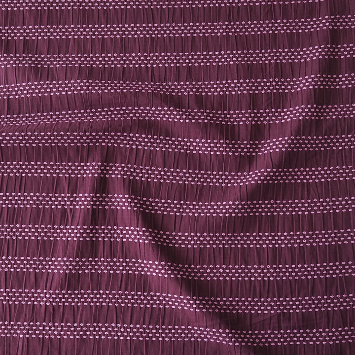 A close-up of a textured fabric with a smocked horizontal stripe pattern in deep plum purple and light lavender.