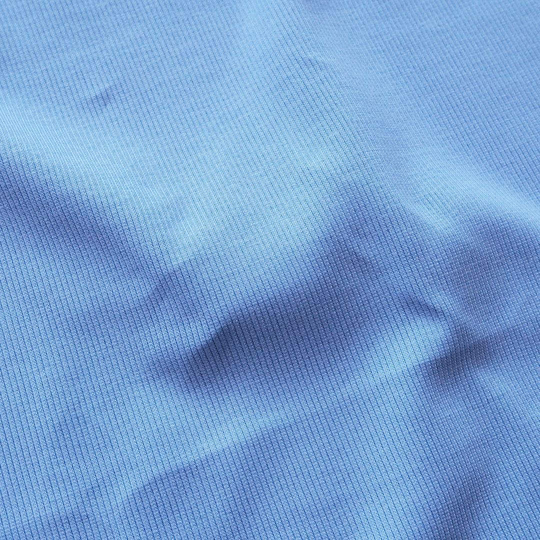A close-up of a blue ribbed knit fabric texture with soft folds and shadows.
