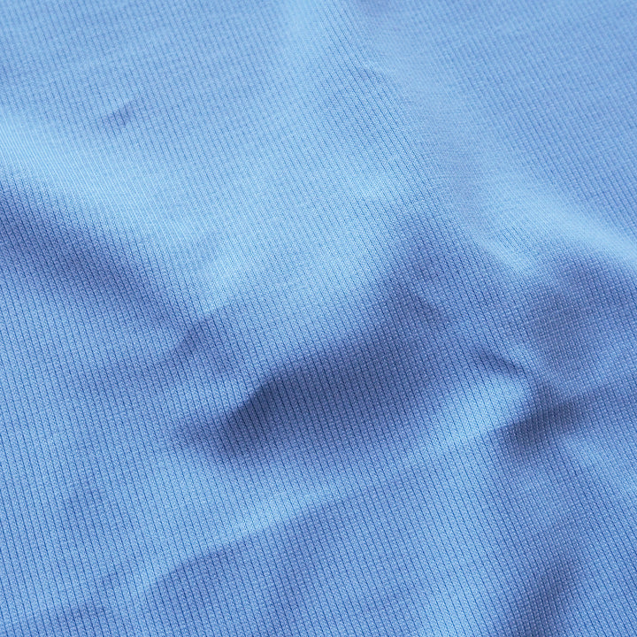 A close-up of a blue ribbed knit fabric texture with soft folds and shadows.