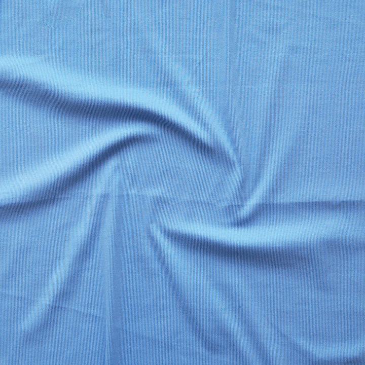 A close-up of light blue fabric with a subtle woven texture, arranged with soft swirls and folds.