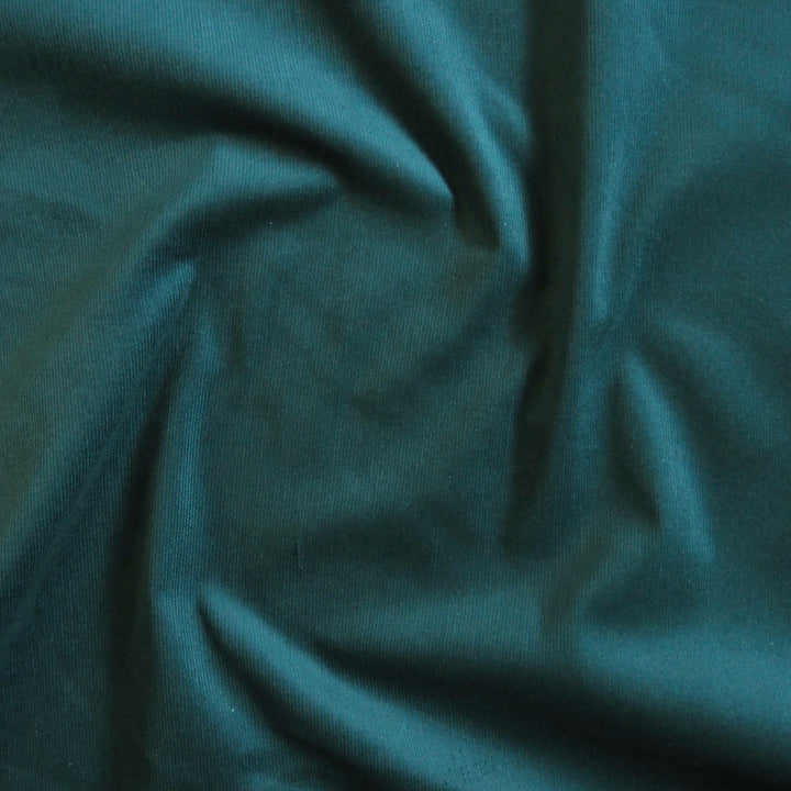 Peacock blue stretch cotton needlecord fabric, soft corduroy texture.