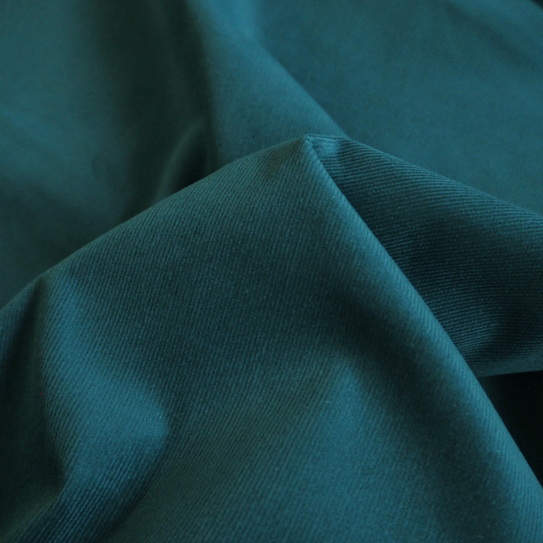 Peacock blue stretch cotton needlecord fabric, soft corduroy texture.