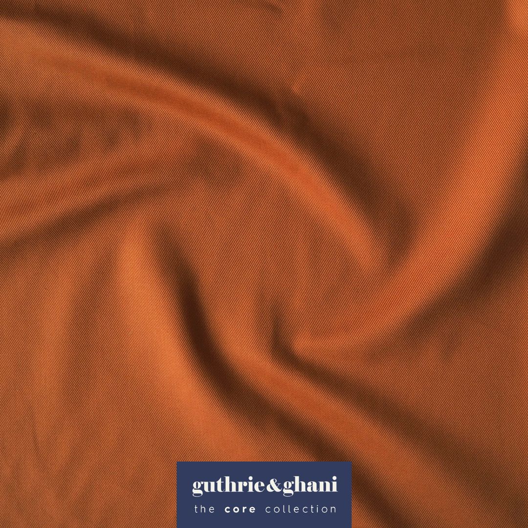 Close-up of rust orange fabric with 'guthrie & ghani' logo in the corner