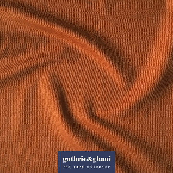 Close-up of rust orange fabric with 'guthrie & ghani' logo in the corner