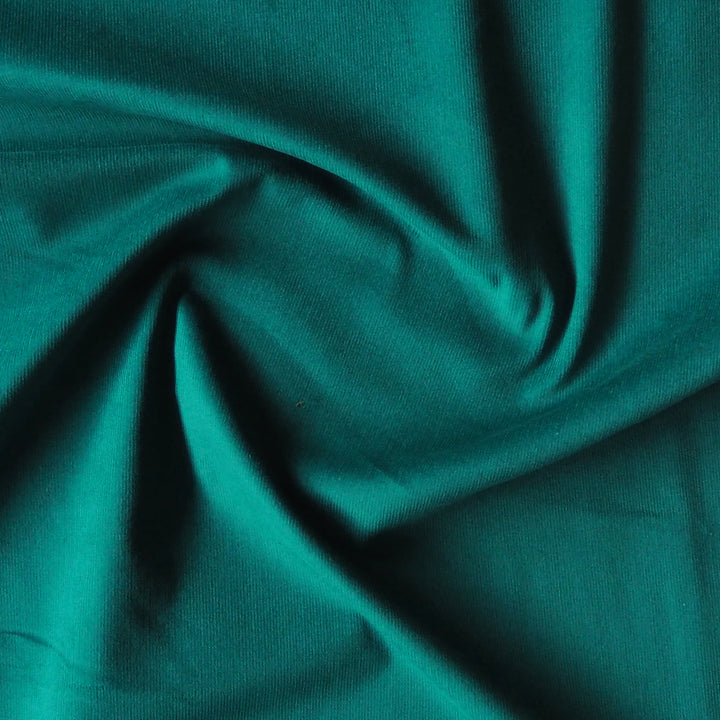 Emerald green stretch cotton needlecord fabric, soft fine cord texture.