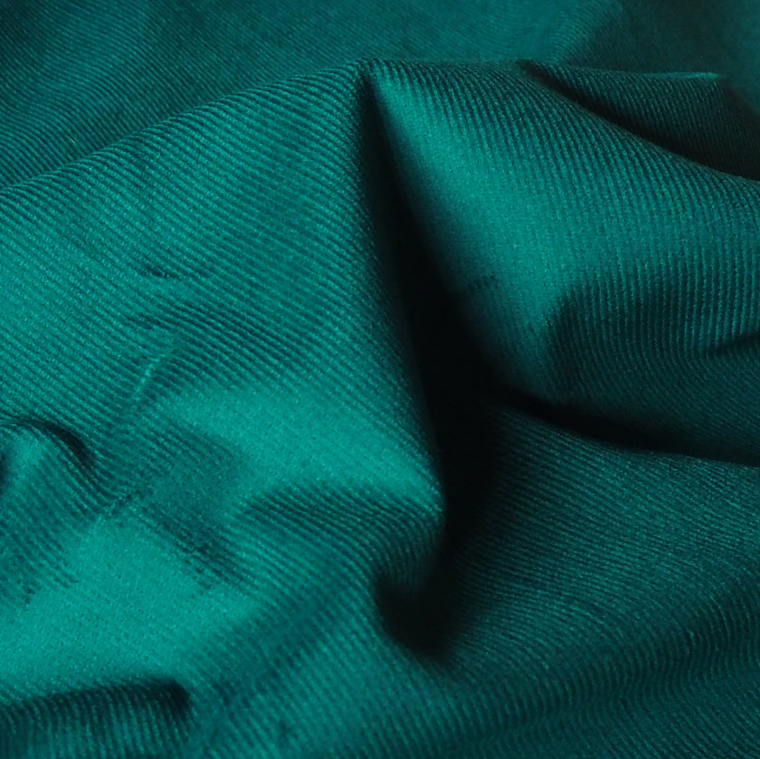Emerald green stretch cotton needlecord fabric, soft fine cord texture.