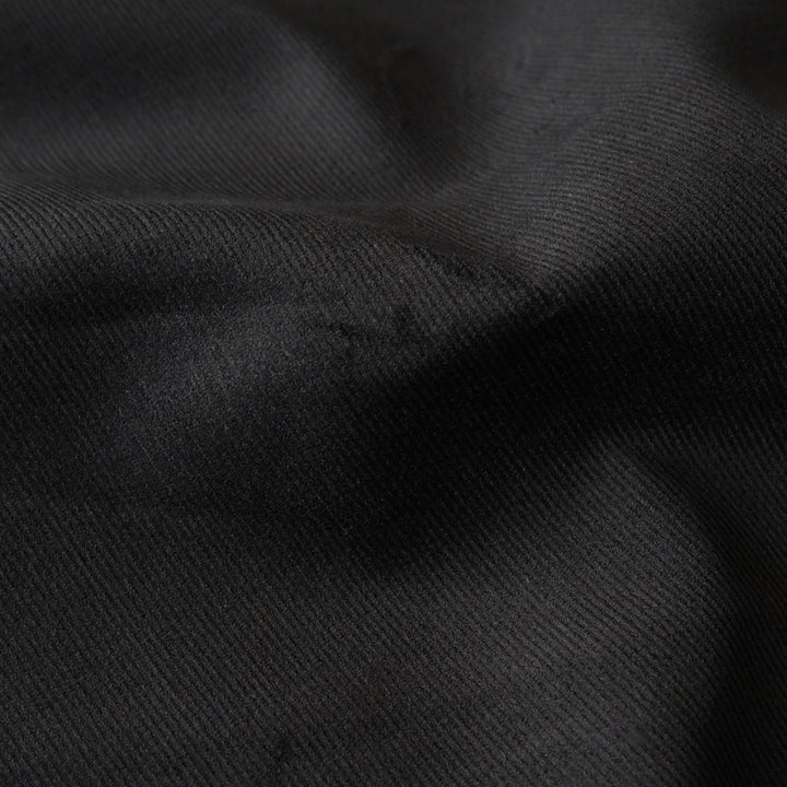 Black stretch cotton needlecord fabric, soft fine cord texture.