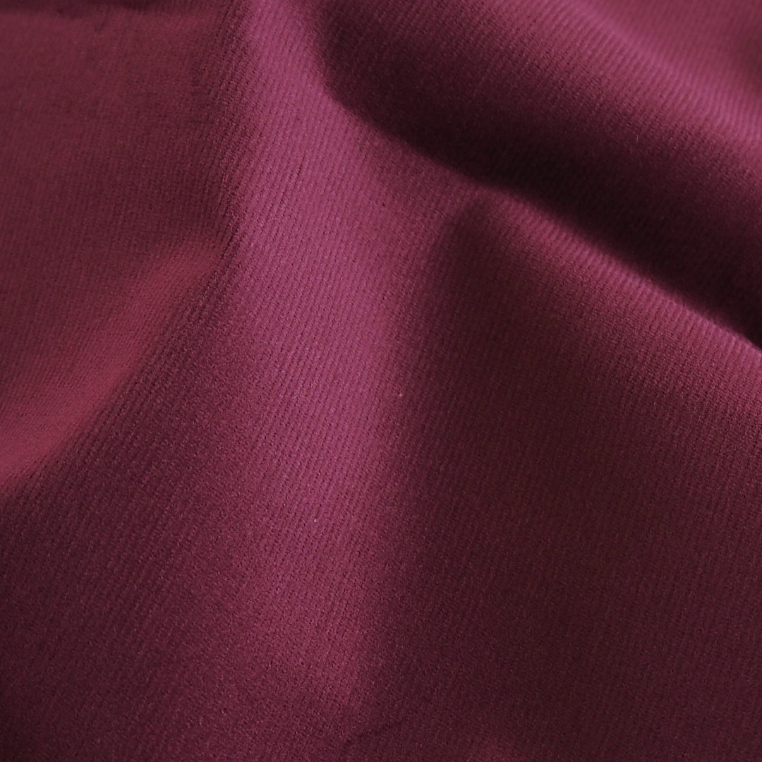 Cranberry red stretch cotton needlecord fabric, fine cord texture.