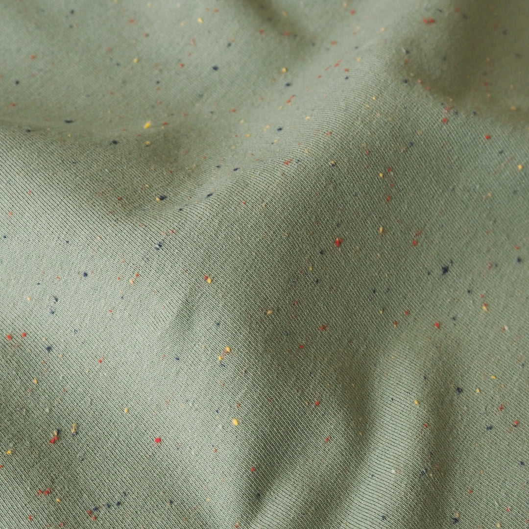 Sage green fleeceback sweatshirt fabric with colourful flecks.