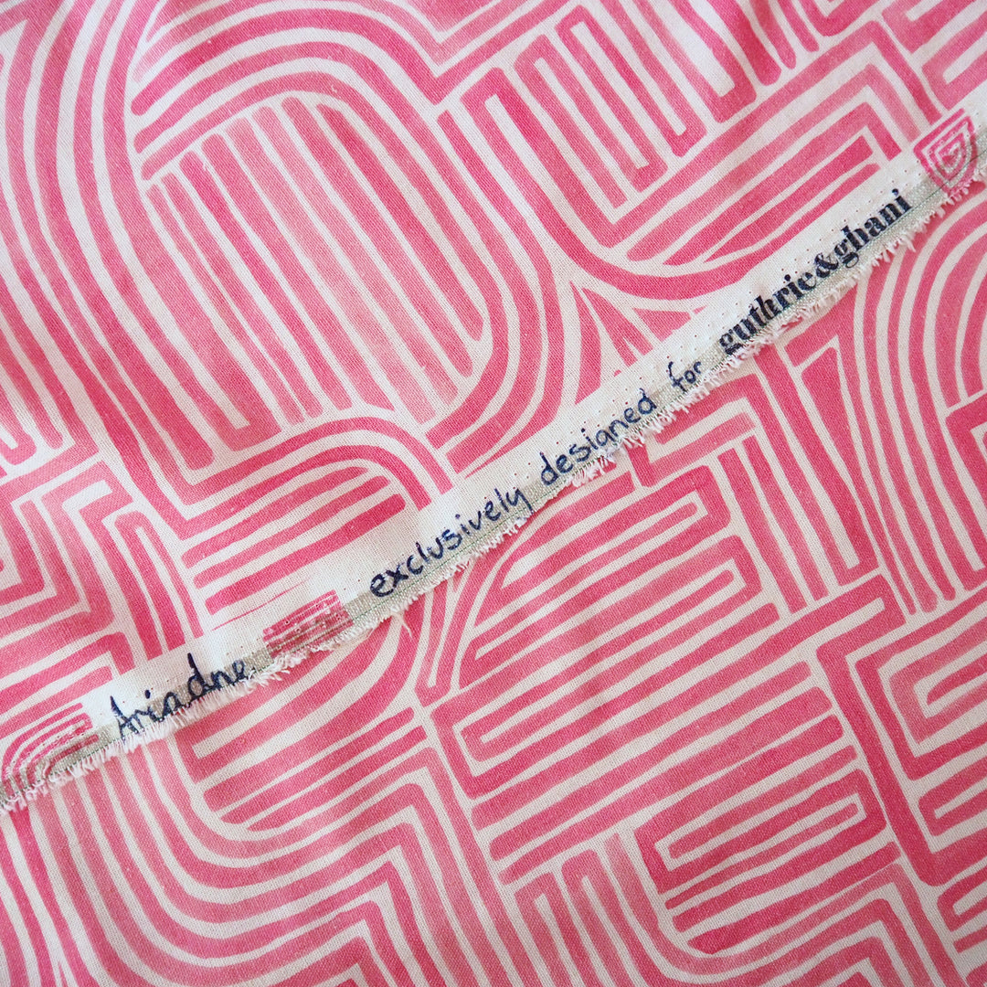 Fabric with pink and white geometric pattern and a label on a pink background