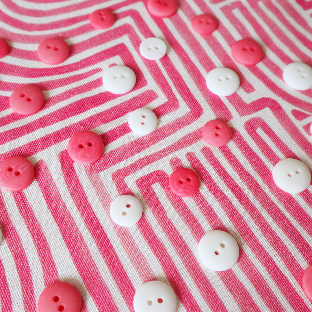 Pink and white buttons on a pink and white striped fabric background