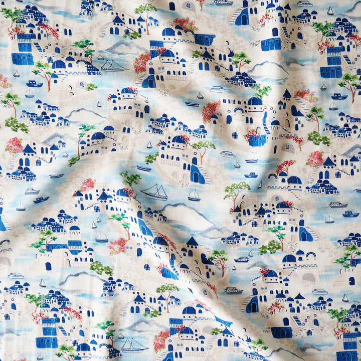 Patterned fabric with blue and white houses, trees, and boats on a beige background