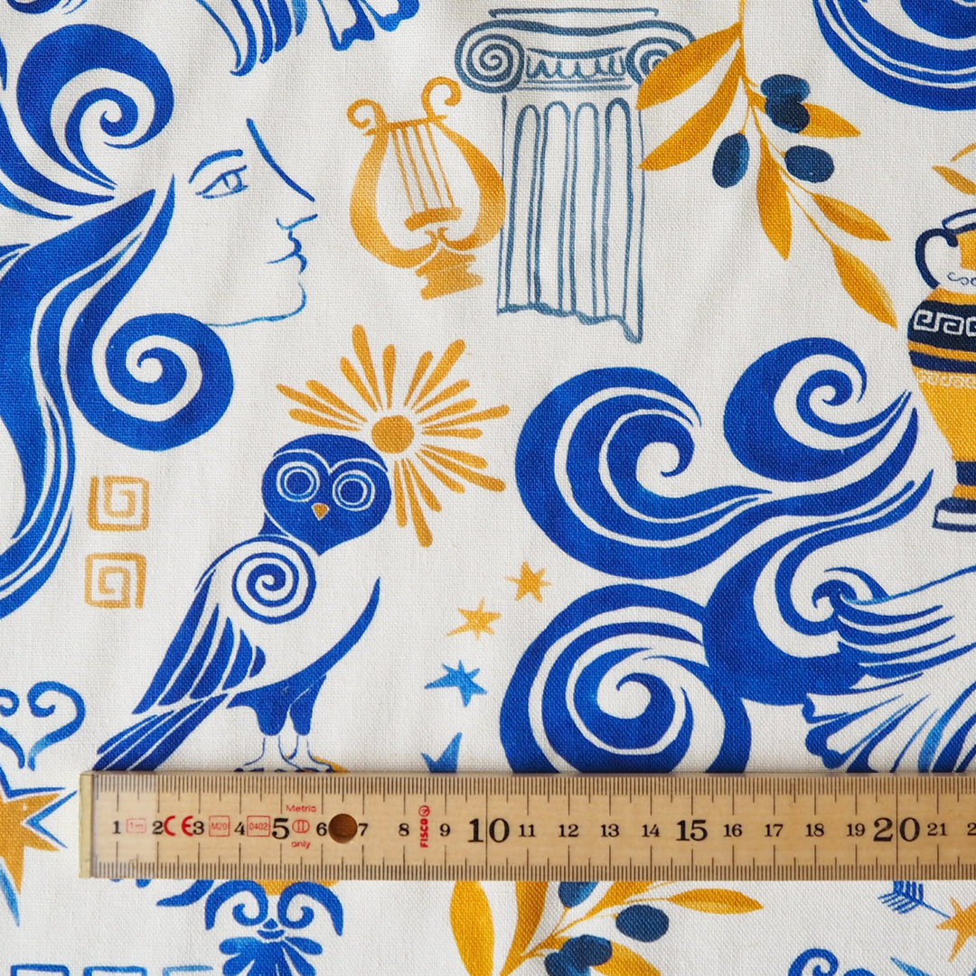 Fabric with Greek-themed design featuring blue, yellow, and white patterns, ruler for scale.