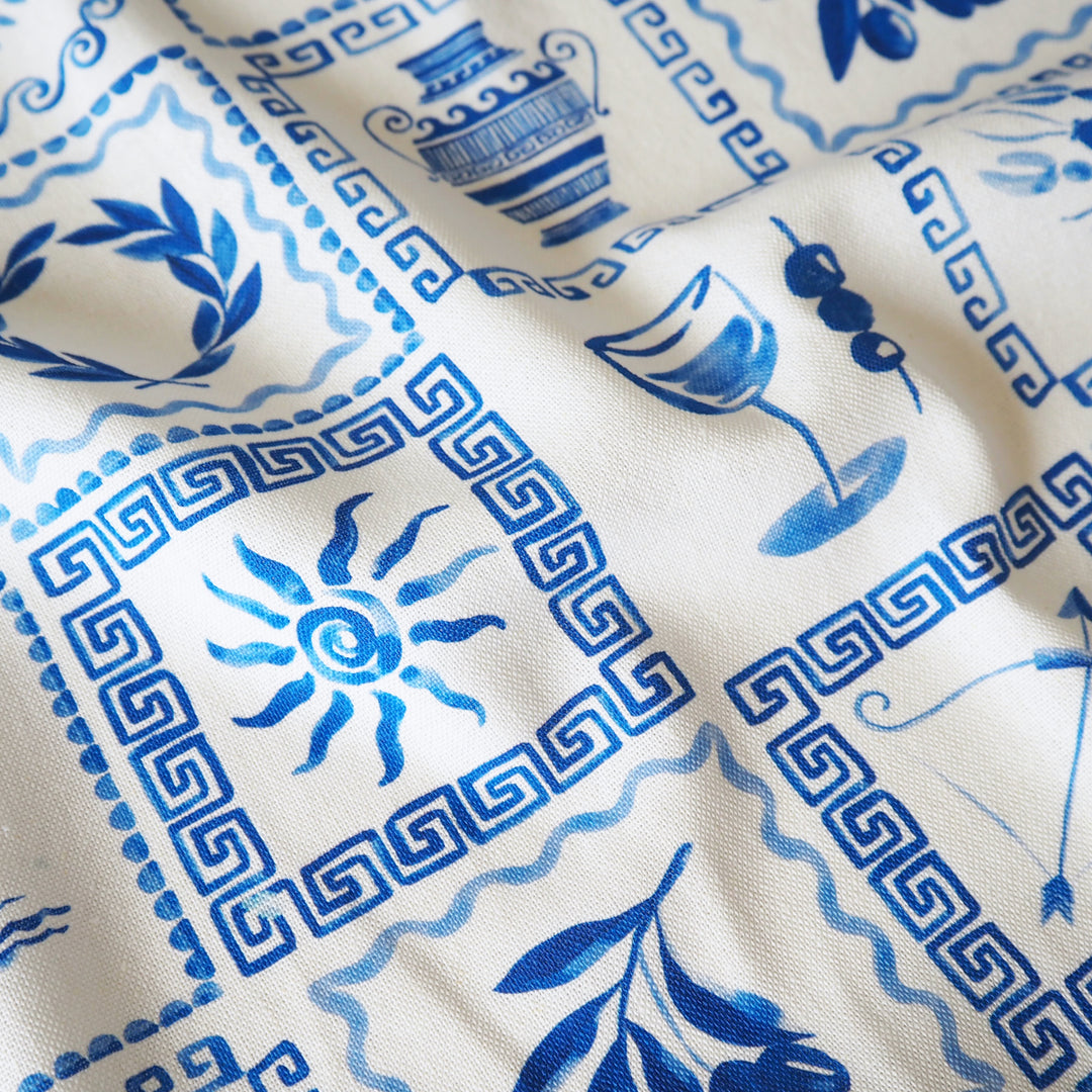 Close-up of fabric with blue and white patterns, including urns and sun designs.
