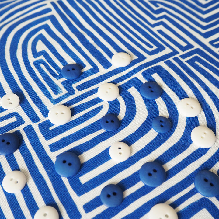 Blue and white buttons scattered on a blue and white patterned fabric background