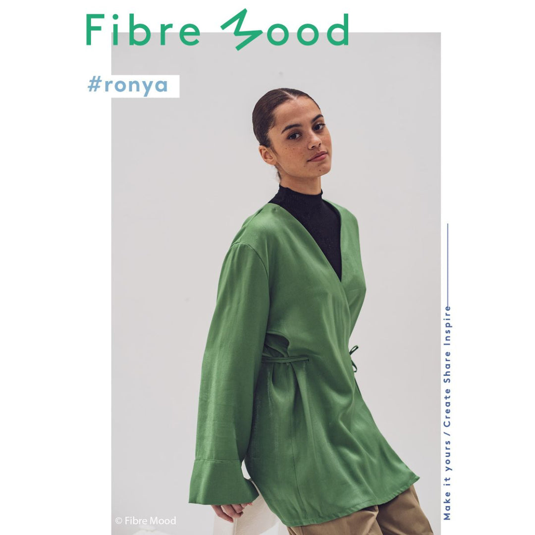 Woman wearing a green jacket with 'Fibre Mood' branding on a light gray background