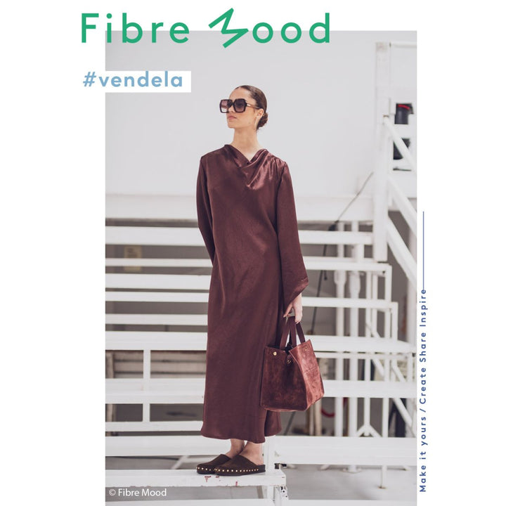 Woman wearing a brown dress and sunglasses with 'Fibre Mood' branding.