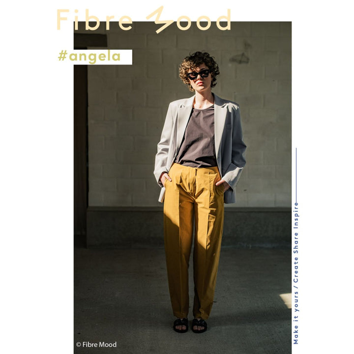 Person wearing a light gray blazer and mustard yellow pants with 'Fibre Mood' branding.