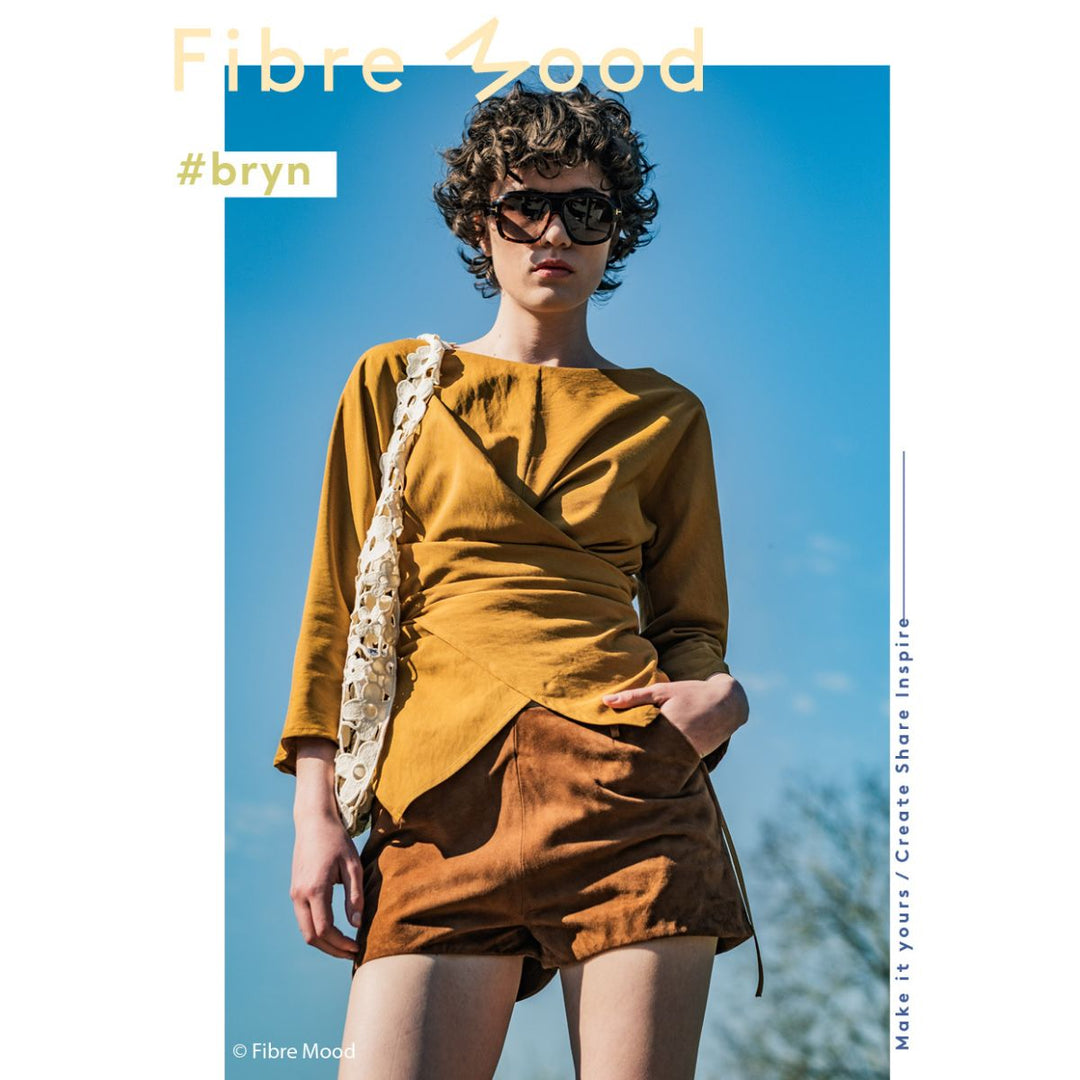 Person wearing a mustard yellow outfit with sunglasses, standing against a blue sky.