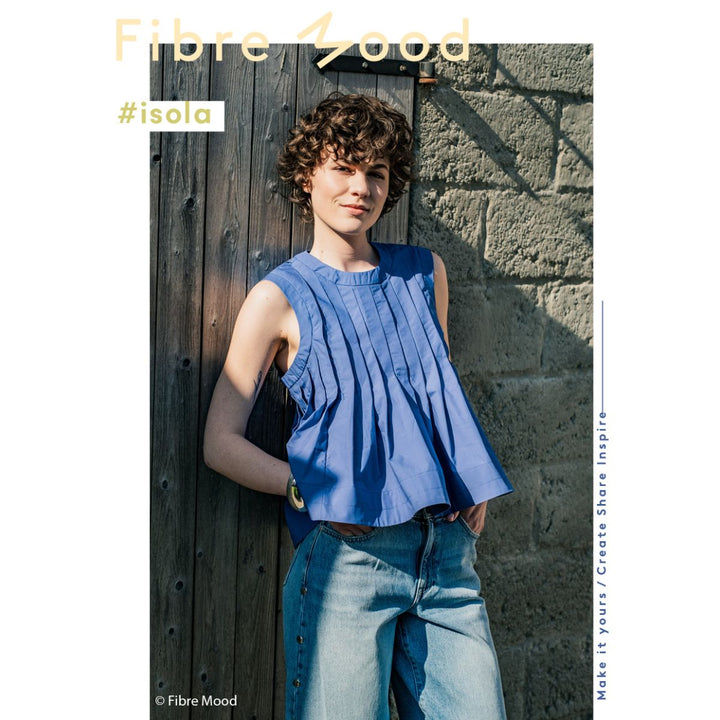 Person wearing a blue top and jeans leaning against a wooden door with 'Fibre Mood' branding.