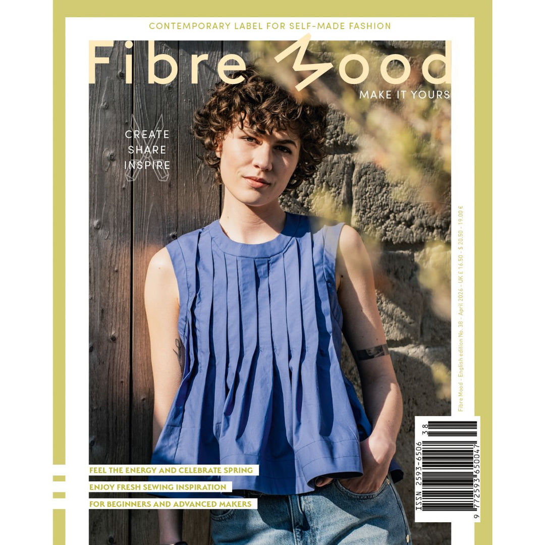 Magazine cover with a person wearing a blue sleeveless top against a wooden wall.