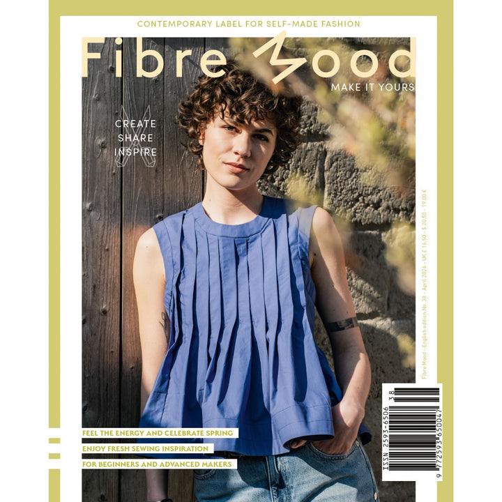 Magazine cover with a person wearing a blue sleeveless top against a wooden wall.
