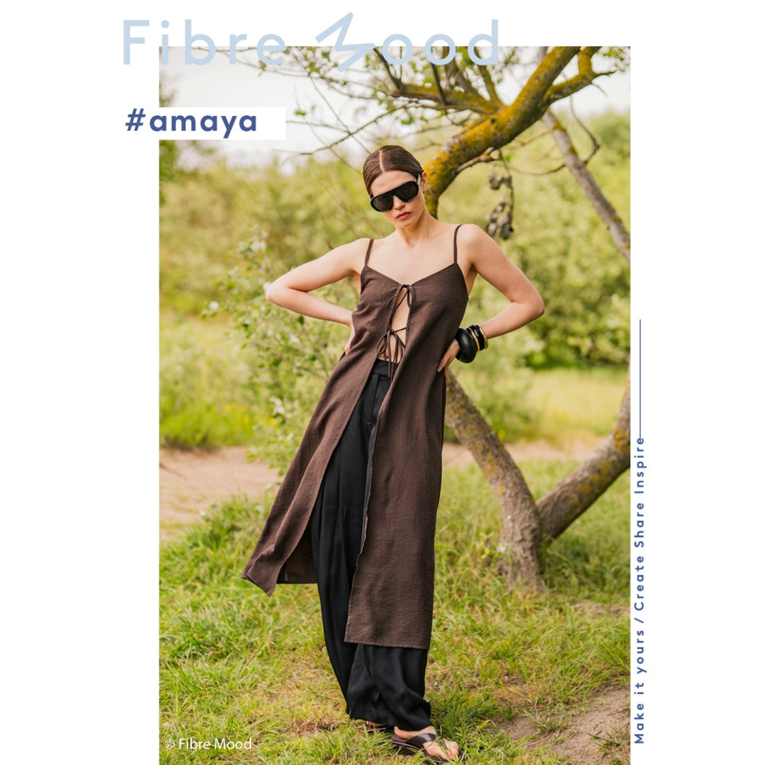 Woman in a brown dress standing in a natural setting with 'Fibre Mood' branding.