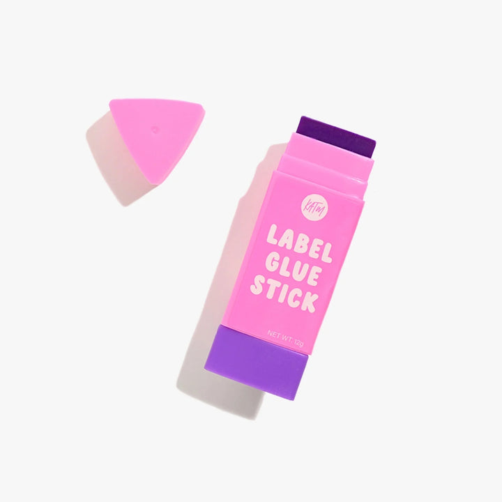 A pink and purple stick of label glue with its triangular pink cap removed and placed beside it on a clean white background.