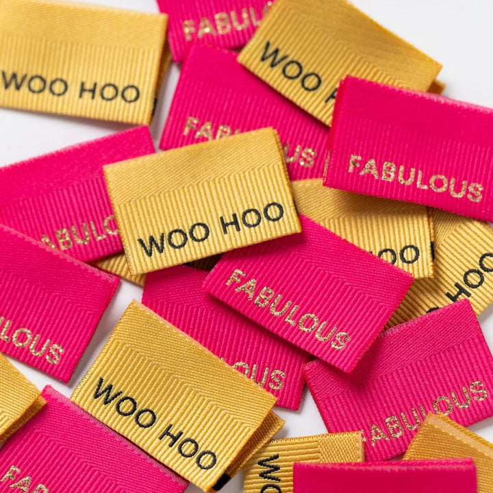 Colorful woven labels with text 'WOO HOO' and 'FABULOUS' on a white background