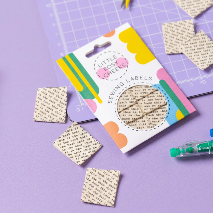 Pack of sewing labels with colorful packaging on a purple surface